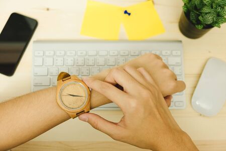 hand of business woman wearing wood watch has smart phone, mouse, plant and keyboard placed on wooden table are background. image for equipment, accessory, fashion, hardware, business conceptの写真素材