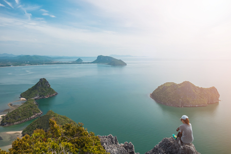 adventure sport background expressive sad alone young woman sit on top of mountain with sea. image for nature, journey, landscape, travel, success, extreme, concept の写真素材