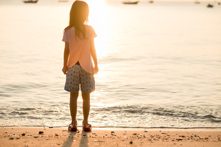 travel background girl stand alone on beach looking beautiful sea sunset. image for person, nature, portrait, landscape, scenery, seascape, evening conceptの写真素材