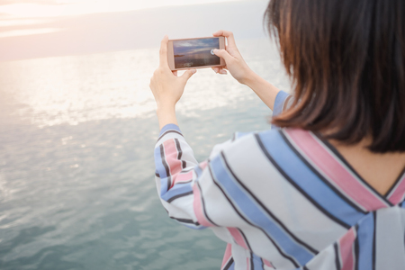 nature background young women stand alone hold mobile phone expression for photography sea. image...