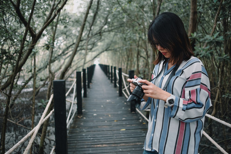 young women photography with camera, wooden bridge and beautiful forest, tree background. image for travel, nature, wild, scenery, lifestyle, tourist, outdoor conceptの写真素材