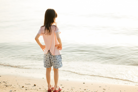 travel background girl stand alone on beach looking beautiful sea sunset. image for person, nature, portrait, landscape, scenery, seascape, evening conceptの写真素材