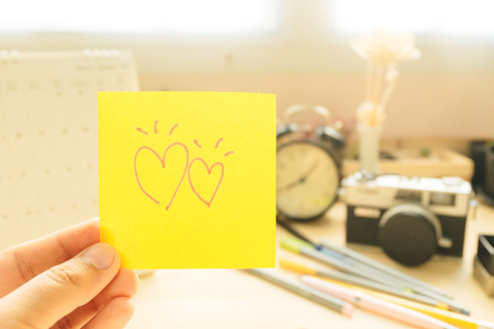hand of woman hold post note with couple heart and equipment business background. image for copy space, business, office, love, body, celebration, workplace conceptの写真素材