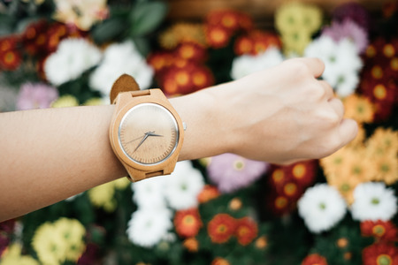 hand business woman wearing wooden watch with copy space and beautiful colorful flowers background. image for valentine, nature, ornamental, accessory, blossom, spring, decorate, garden conceptの写真素材