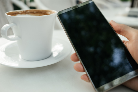 food and technology background hand of businessman hold mobile phone for photography with coffee and copy space. image for coffee art, beverage, smart phone, body, business conceptの写真素材