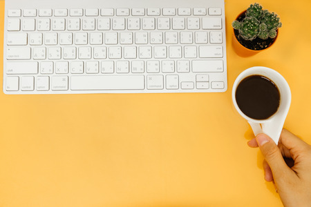 top view business table bakground hand of woman hold coffee cup with keyboard and plant on table. image for copy space, desktop, drink, workplace, workspace, education, technology concept の写真素材