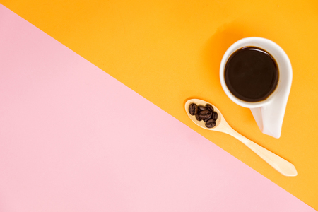 top view. beverage background cup with coffee, wooden spoon and coffee beans placed on yellow and pink table. image for copy space, food, drink, isolated, cafe, business conceptの写真素材