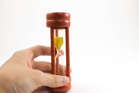 white background hand of caucasian woman hold wooden sand clock with copy space. image for isolate,...