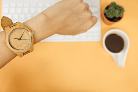 top view hand of caucasian business woman wearing wooden watch with keyboard, coffee and plant on table background. image for copy space, desktop, workplace, workspace, education, technology concept の写真素材