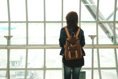 travel background young caucasian woman with backpack stand alone in airport terminal. image for tourist, person, transport, lifestyle conceptの写真素材