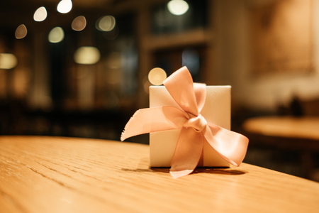 celebration background gift box place on wood table in restaurant with copy space. image for present, birthday, christmas, object, decoration, nobody, holiday conceptの写真素材