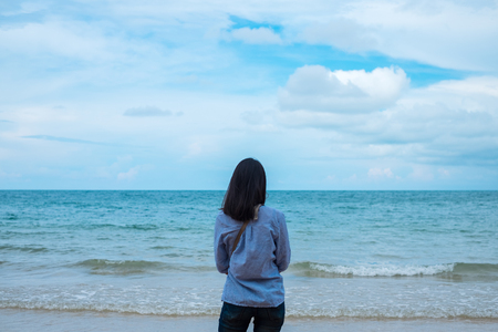 travel background back view young woman standing alone on beach. image for summer, person, portrait, scenery, tropical conceptの写真素材