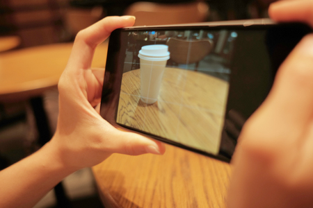 technology background hand of woman using mobile phone take coffee glass photo with copy space. image for modern, food, beverage, lifestyle, camera conceptの写真素材