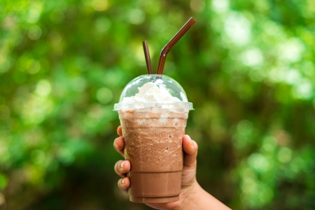food background hand of woman hold coffee with milk froth on top. image for beverage, nature, body, drink conceptの写真素材