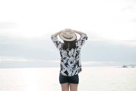 traveler young woman in casual dress with hat standing alone on beach has sea backgroundの写真素材