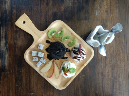 delicious flavor ice cream set  with apple, kiwi fruit and chocolate cake in wooden tray placed on wooden table backgroundの写真素材