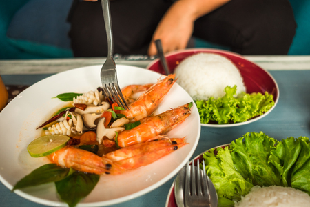 delicious thailand food fried shrimp and squid cooked herb in dish with rice on wood table backgroundの写真素材
