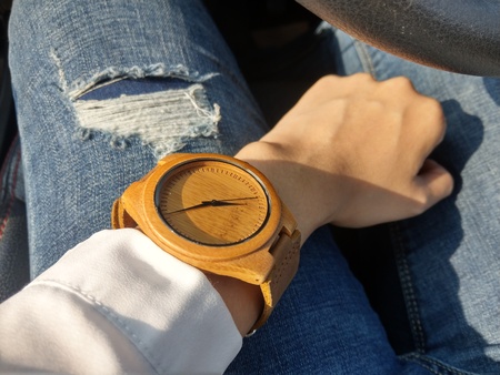 hand of caucasian women wearing wood watch with jean pants backgroundの写真素材