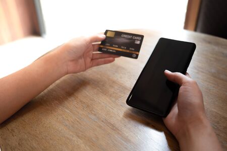 closeup businessman using blank screen mobile phone and credit card for online payment. image for internet, commerce, technology, shopping, device and lifestyleの写真素材