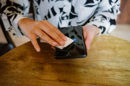 closeup hands of businesswoman using alcohol fabric cleaning blank screen mobile phone for clearing covid-19 virus. image for healthy, hygiene, technology and protectの写真素材