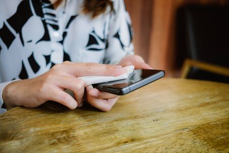 closeup hands of businesswoman using alcohol fabric cleaning blank screen mobile phone for clearing covid-19 virus. image for healthy, hygiene, technology and protectの写真素材