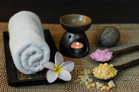 Thai spa massage setting with towel, frangipani and bath salt on spoonの写真素材