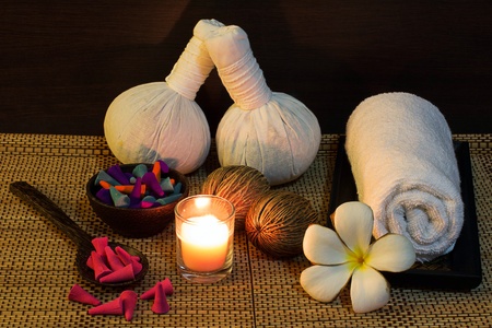 Thai spa massage setting with herbal compress balls, towel, frangipani, candle and incense coneの写真素材