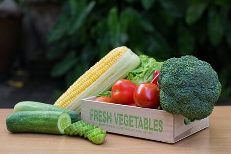 Variety of fresh vegetables in wooden box on wood tableの写真素材