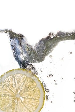 Lemon slice falling into the water on white backgroundの写真素材
