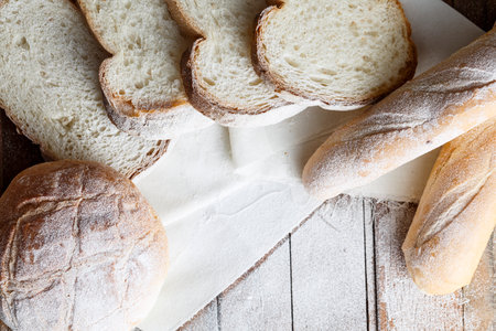 Fresh baked bread and sliced bread on rustic wooden tableの写真素材