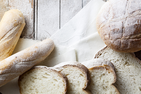 Fresh baked bread and sliced bread on rustic wooden tableの写真素材
