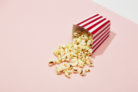 Full of popcorn in classic striped box on color backgroundの写真素材