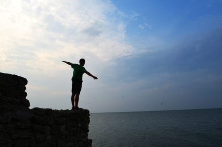 man standing on the ancient wall at the sea shore and holding handsの写真素材