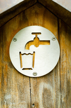 drinking water sign on a sring tap outdoor in park. the tap is wooden and old. closeup vertical composition. ecological concept of saving water and natural resourcesの写真素材