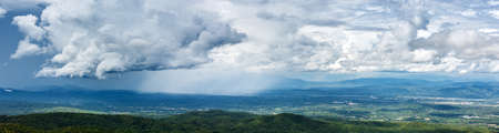Panorama shot of Aerial beautiful dramatic cloudy sky with Rain storm over mountains landscapeの写真素材