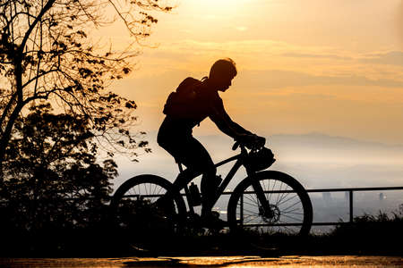 Silhouette of cyclist on mountainbiker at sunsetの写真素材