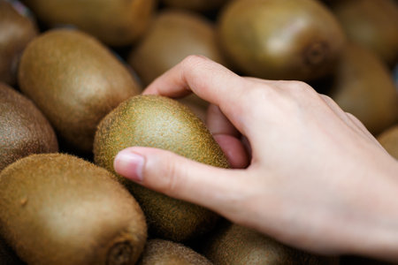 Woman's hand choosing kiwi fruit in supermarketの写真素材