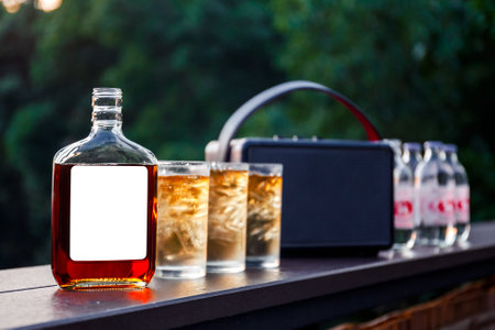 brandy, rum, or bourbon with soda  and golden amber light glass of whiskey with ice on wooden table bar in outdoor parttyの写真素材