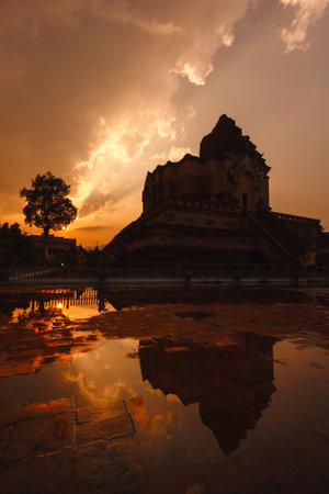 silhouette Ancient broken pagoda at Wat Chedi Luang temple reflection on water at sunsetの写真素材