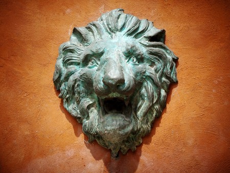 Cast green metal lion head on the orange wallの写真素材