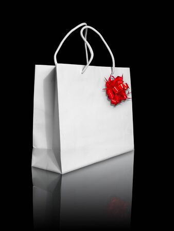 White paper bag and red bow on reflect floor and black backgroundの写真素材