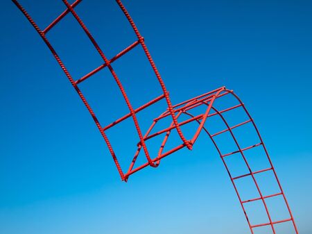 Bending steel painted red and blue sky backgroundの写真素材