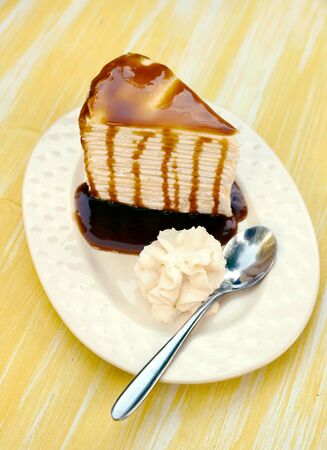 Cream cake topped with caramel and spoon in a ceramic plateの写真素材