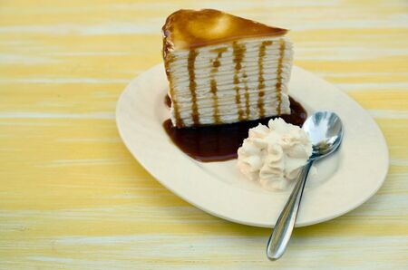 Side of Cream cake topped with caramel and spoon in a ceramic plateの写真素材