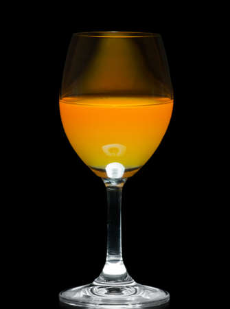 Orange juice in wine glass on black backgroundの写真素材