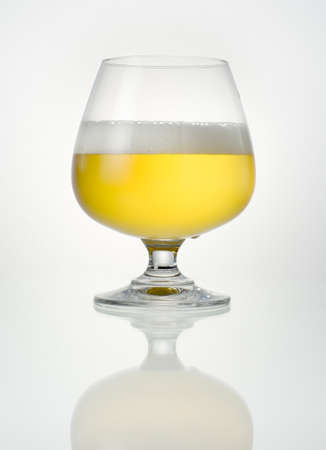 Beer in glass with reflection on a white backgroundの写真素材