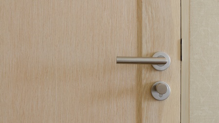 Stainless Steel Handle on light brown wooden doorの写真素材