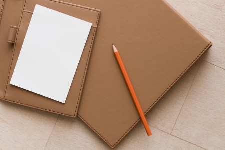 White Paper and Orange Pencil on Brown leather Business Book