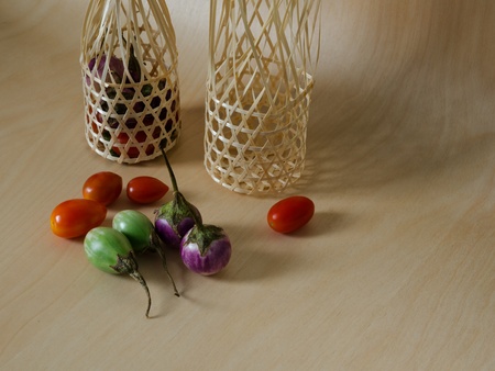 Eggplant Tomato and two bamboo basket on Wood table light and shadowの写真素材