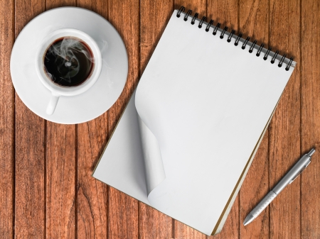 Sketch book Silver pen and White cup of hot coffee on wood tableの写真素材